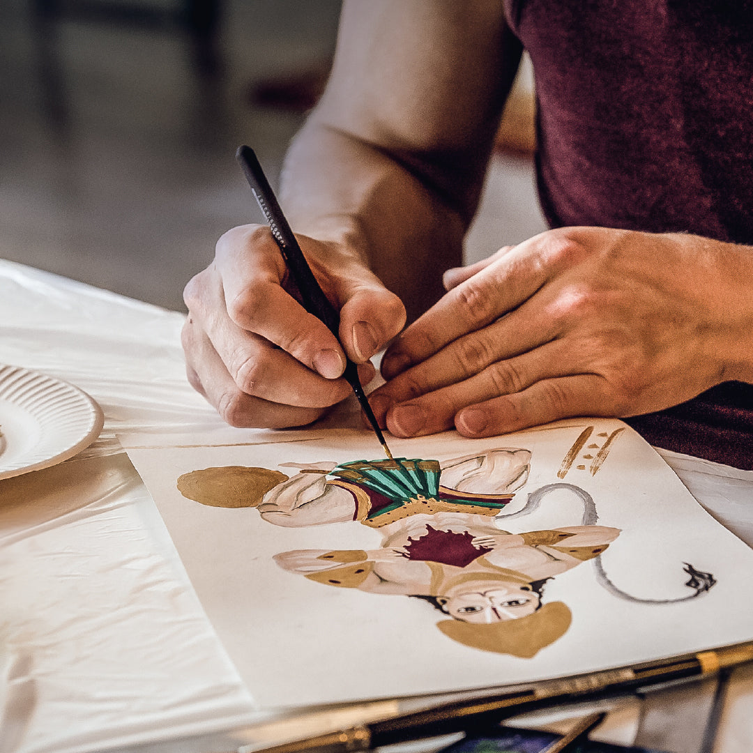 A person's hands are shown engaging in the activity of painting meditation, with focus on the creative process.